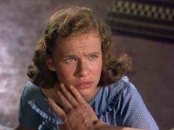 Movie still from “The River” (1951), directed by Jean Renoir – A young woman is sitting down with her hand on her face; Close Up shot, Low angle