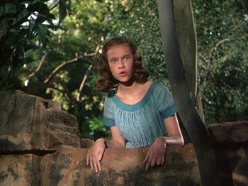 Movie still from “The River” (1951), directed by Jean Renoir – A young girl in a blue dress leaning against a wall; Medium shot, Low angle
