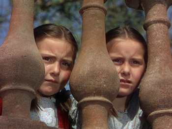 Movie still from “The River” (1951), directed by Jean Renoir – Two young girls are looking through a fence; Close Up shot, Low angle