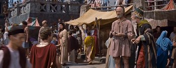 Movie still from “The Robe” (1953), directed by Henry Koster – A group of people standing next to each other on a street; Wide shot, Over the shoulder angle