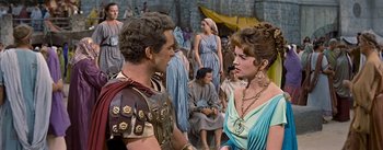 Movie still from “The Robe” (1953), directed by Henry Koster – A man and a woman in roman garb talking to each other in front of a crowd; Medium shot, Over the shoulder angle