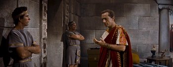 Movie still from “The Robe” (1953), directed by Henry Koster – Two men dressed in ancient roman garb standing in front of a stone wall; Medium shot, Over the shoulder angle