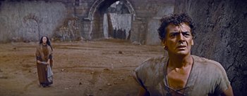 Movie still from “The Robe” (1953), directed by Henry Koster – A woman standing in front of an old stone building; Medium shot, Low angle