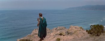 Movie still from “The Robe” (1953), directed by Henry Koster – A man in a toga stands on a cliff overlooking the ocean; Extreme Wide shot, High angle