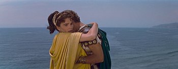 Movie still from “The Robe” (1953), directed by Henry Koster – A man and a woman embracing each other on the beach; Medium shot, Over the shoulder angle