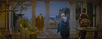 Movie still from “The Robe” (1953), directed by Henry Koster – Two men in robes are standing in front of an ocean view; Extreme Wide shot, High angle