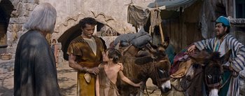 Movie still from “The Robe” (1953), directed by Henry Koster – A man and a boy standing next to a donkey; Medium shot, Over the shoulder angle