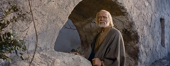 Movie still from “The Robe” (1953), directed by Henry Koster – An old man standing in front of a rock cave; Medium shot, Low angle
