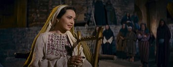 Movie still from “The Robe” (1953), directed by Henry Koster – A woman sitting in a chair holding a harp; Medium shot, Over the shoulder angle