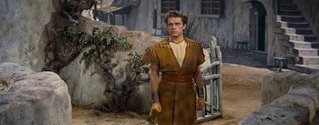 Movie still from “The Robe” (1953), directed by Henry Koster – A man dressed in a costume standing in front of a fence; Medium shot, Low angle