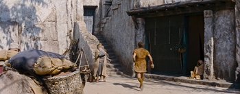 Movie still from “The Robe” (1953), directed by Henry Koster – A man is running down the street while another man is walking; Wide shot, High angle