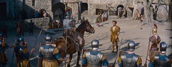 Movie still from “The Robe” (1953), directed by Henry Koster – A group of men in medieval garb standing next to a horse; Wide shot, High angle