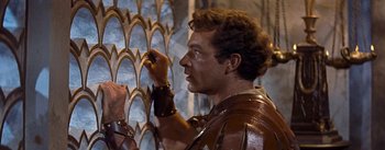 Movie still from “The Robe” (1953), directed by Henry Koster – A man in a roman outfit painting a wall; Close Up shot, Low angle