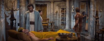 Movie still from “The Robe” (1953), directed by Henry Koster – A man laying on a bed next to a woman in a room; Medium shot, High angle