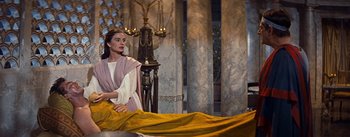 Movie still from “The Robe” (1953), directed by Henry Koster – A woman sitting in front of a bed in a room; Medium shot, Low angle