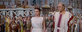 Movie still from “The Robe” (1953), directed by Henry Koster – A woman in a white dress standing in front of a group of men; Medium shot, Low angle