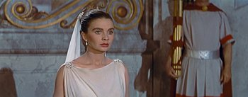 Movie still from “The Robe” (1953), directed by Henry Koster – A woman in a white dress standing in front of a wall; Close Up shot, Over the shoulder angle