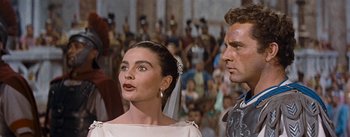 Movie still from “The Robe” (1953), directed by Henry Koster – A man and a woman standing next to each other in front of a crowd; Close Up shot, Low angle