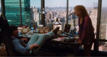 Movie still from “The Rose” (1979), directed by Mark Rydell – Two people sitting at a desk in front of a large window; Wide shot, High angle