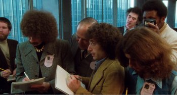 Movie still from “The Rose” (1979), directed by Mark Rydell – A group of people standing around each other in a room; Medium shot, Over the shoulder angle