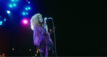 Movie still from “The Rose” (1979), directed by Mark Rydell – A woman in a purple dress singing on a stage; Wide shot, Low angle