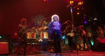 Movie still from “The Rose” (1979), directed by Mark Rydell – A group of people on a stage with a microphone; Wide shot, Low angle