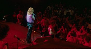Movie still from “The Rose” (1979), directed by Mark Rydell – A person on a stage singing into a microphone; Wide shot, High angle