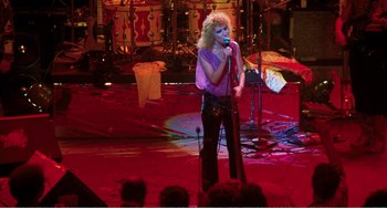 Movie still from “The Rose” (1979), directed by Mark Rydell – A woman is singing into a microphone on a stage; Wide shot, High angle