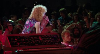 Movie still from “The Rose” (1979), directed by Mark Rydell – A woman singing into a microphone at a concert; Medium shot, Low angle
