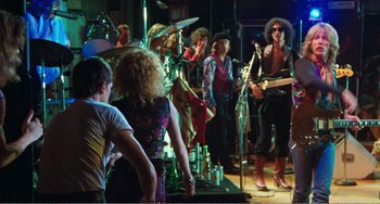 Movie still from “The Rose” (1979), directed by Mark Rydell – A group of people standing in front of a band; Wide shot, Over the shoulder angle