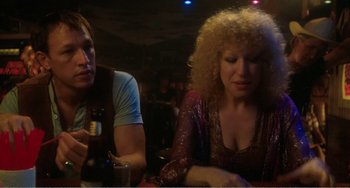 Movie still from “The Rose” (1979), directed by Mark Rydell – A woman sitting next to a man at a bar; Close Up shot, Over the shoulder angle