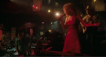 Movie still from “The Rose” (1979), directed by Mark Rydell – A woman singing into a microphone at a bar; Wide shot, Low angle