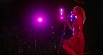 Movie still from “The Rose” (1979), directed by Mark Rydell – A woman in a red dress singing on a stage; Wide shot, Low angle