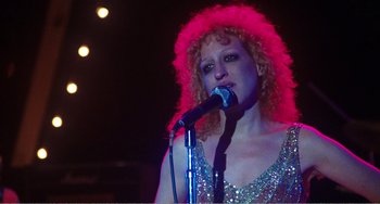 Movie still from “The Rose” (1979), directed by Mark Rydell – A woman with curly red hair singing into a microphone; Close Up shot, Low angle