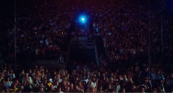 Movie still from “The Rose” (1979), directed by Mark Rydell – A crowd of people sitting and standing in a stadium at night; Extreme Wide shot, High angle