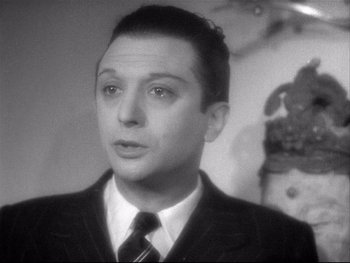 Movie still from “The Rules of the Game” (1939), directed by Jean Renoir – A black and white photo of a man wearing a suit and tie; Close Up shot, Low angle