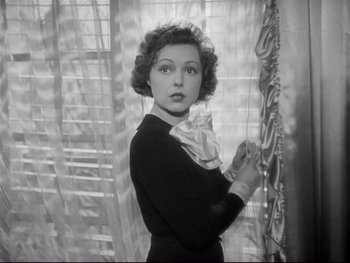 Movie still from “The Rules of the Game” (1939), directed by Jean Renoir – An old black and white photo of a woman standing in front of a window; Close Up shot, High angle