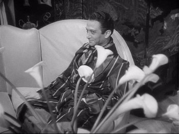 Movie still from “The Rules of the Game” (1939), directed by Jean Renoir – A black and white photo of a man sitting in a chair; Medium shot, High angle