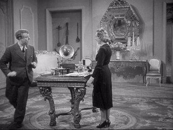 Movie still from “The Rules of the Game” (1939), directed by Jean Renoir – A man and a woman standing in front of an antique desk; Wide shot, High angle