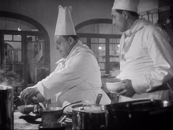 Movie still from “The Rules of the Game” (1939), directed by Jean Renoir – Two men in chef's hats preparing food in a kitchen; Medium shot, Low angle