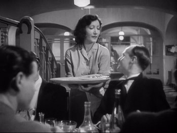 Movie still from “The Rules of the Game” (1939), directed by Jean Renoir – A woman holding a tray of food in front of two men; Medium shot, Low angle