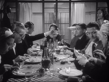 Movie still from “The Rules of the Game” (1939), directed by Jean Renoir – A black and white photo of a group of people sitting at a table; Medium shot, High angle