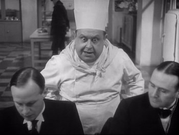 Movie still from “The Rules of the Game” (1939), directed by Jean Renoir – A black - and - white photo of a man wearing a chef's hat; Medium shot, Low angle