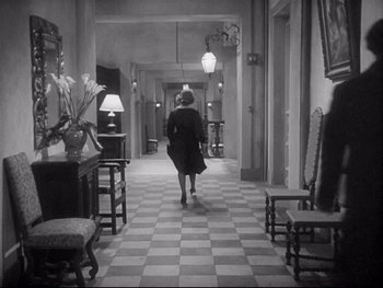 Movie still from “The Rules of the Game” (1939), directed by Jean Renoir – A woman walking down a hall way in a building; Wide shot, High angle