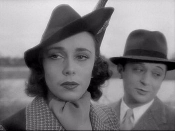 Movie still from “The Rules of the Game” (1939), directed by Jean Renoir – A woman wearing a hat with a man standing next to her; Close Up shot, Over the shoulder angle