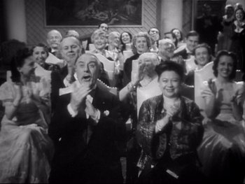 Movie still from “The Rules of the Game” (1939), directed by Jean Renoir – A group of people standing in front of each other clapping; Medium shot, Low angle