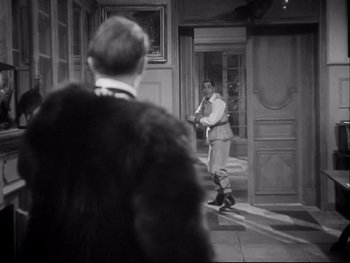 Movie still from “The Rules of the Game” (1939), directed by Jean Renoir – A man standing in front of another man in front of a building; Medium shot, Over the shoulder angle