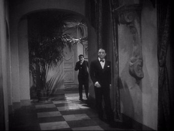 Movie still from “The Rules of the Game” (1939), directed by Jean Renoir – Two men in tuxedos standing in a hallway; Wide shot, High angle