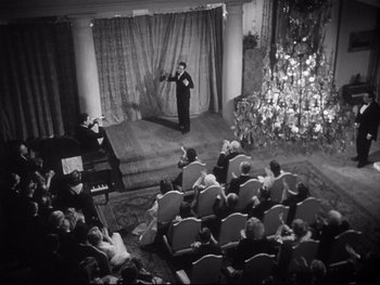 Movie still from “The Rules of the Game” (1939), directed by Jean Renoir – An old photo of a man performing on a stage; Extreme Wide shot, High angle
