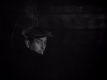 Movie still from “The Rules of the Game” (1939), directed by Jean Renoir – A man wearing a hat is smoking a cigarette; Close Up shot, High angle